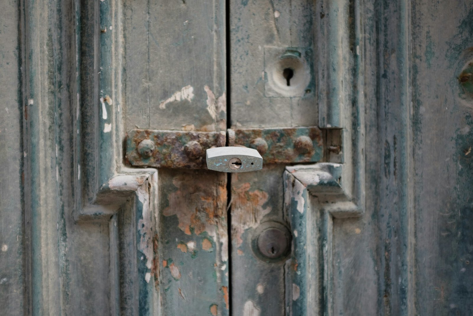 Padlock and rusted latch on a weathered timber door